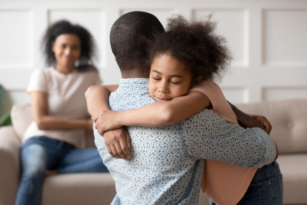 dad hugging girl while mom watches